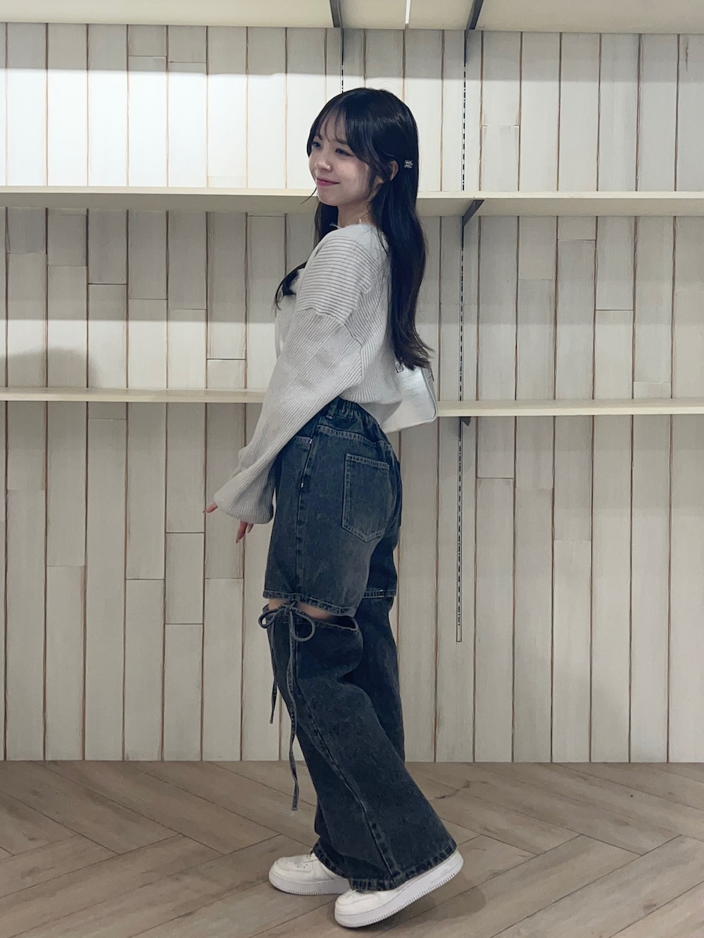 ブルー系のアンサンブル、ブラック系のデニムパンツ、シルバー系のショルダーバッグを着用したレディースの秋コーディネートの5枚目の写真