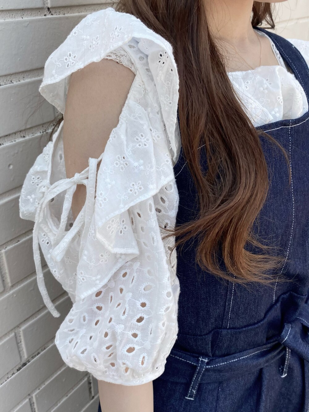 ホワイト系のサンダル、ブルー系のジャンパースカート、ブラック系のトートバッグを着用したレディースの春コーディネートの2枚目の写真