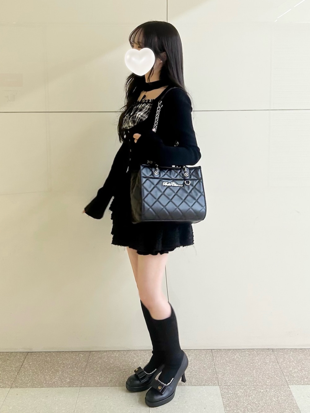ブラック系のスカート、ブラック系のトートバッグ、ブラック系のブーツを着用したレディースの春コーディネートの4枚目の写真