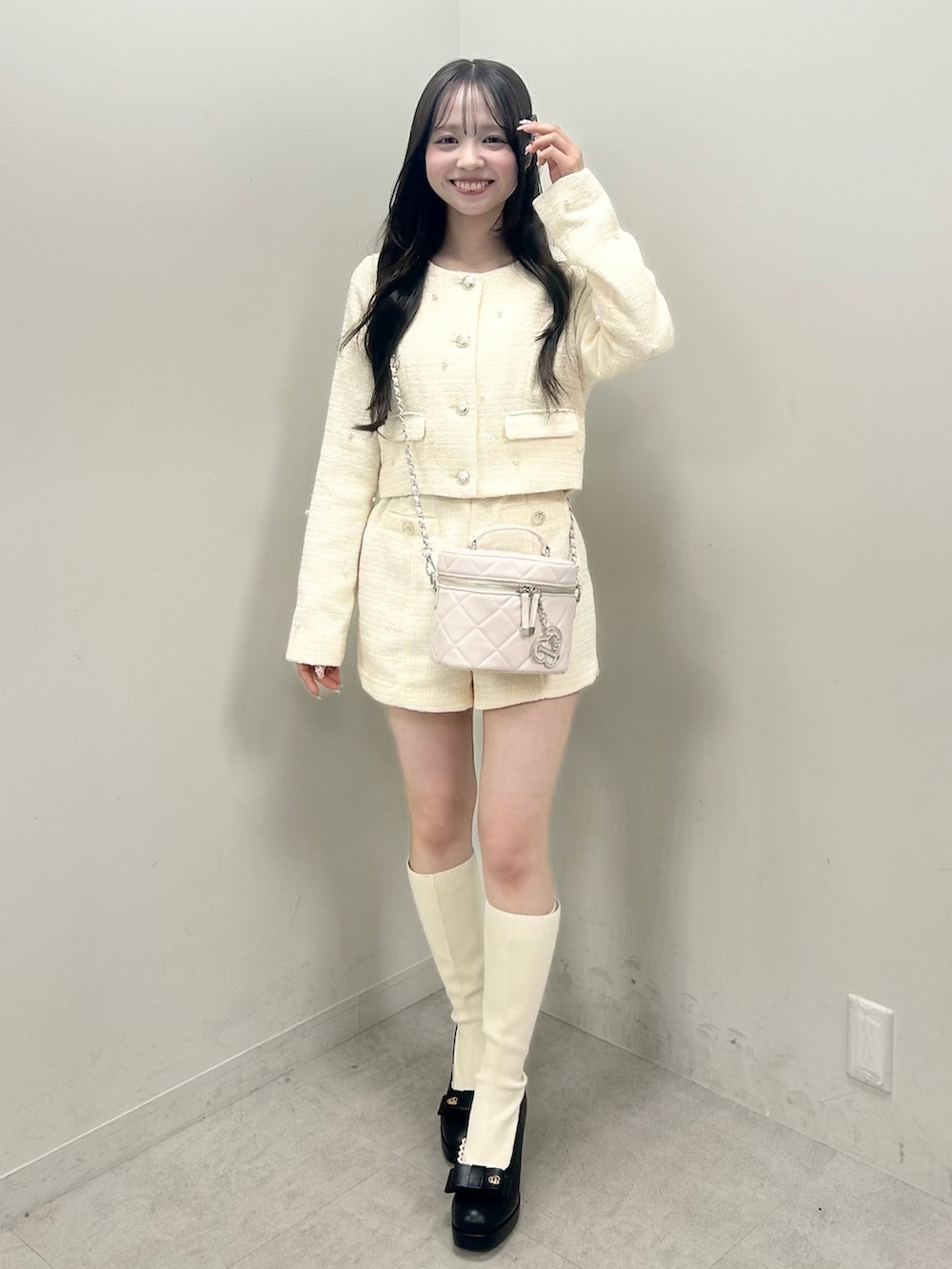 ホワイト系のノーカラージャケット、ホワイト系のブーツ、ホワイト系のショルダーバッグを着用したレディースの春コーディネートの2枚目の写真