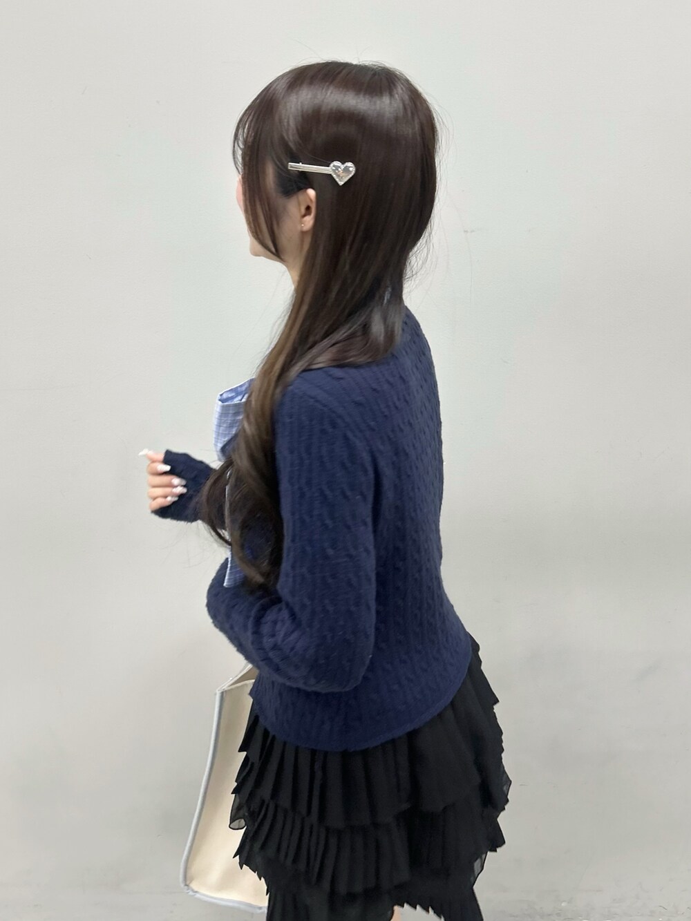 ブルー系のニット/セーター、ブラック系のスカート、ブルー系のトートバッグを着用したレディースの冬コーディネートの7枚目の写真