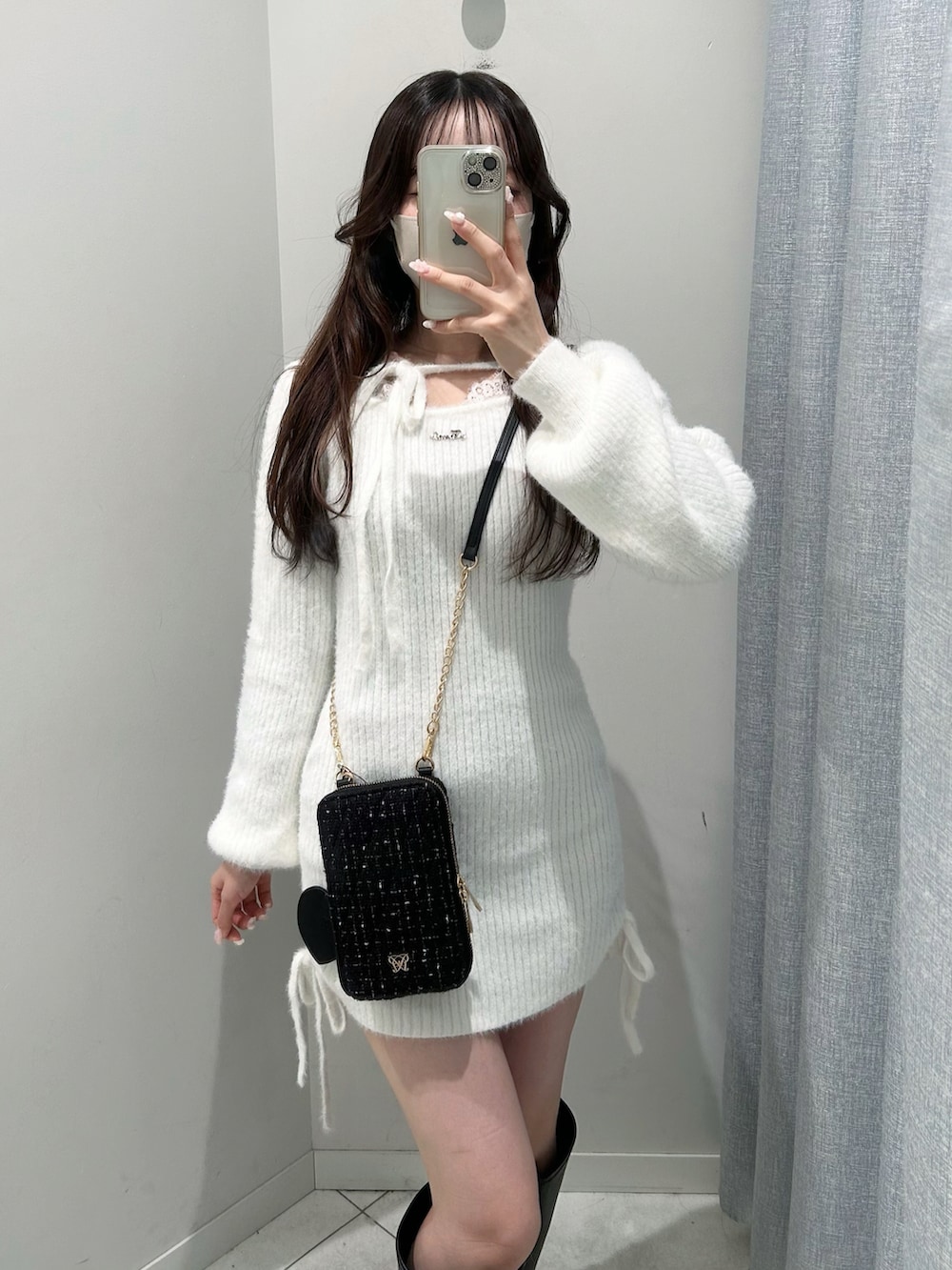 ブラック系のショルダーバッグ、ブラック系のブーツ、ホワイト系のワンピースを着用したレディースの秋コーディネートの2枚目の写真