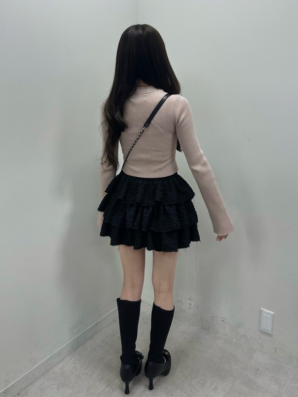 ベージュ系のニット/セーター、ブラック系のスカート、ブラック系のショルダーバッグを着用したレディースの春コーディネートの4枚目の写真