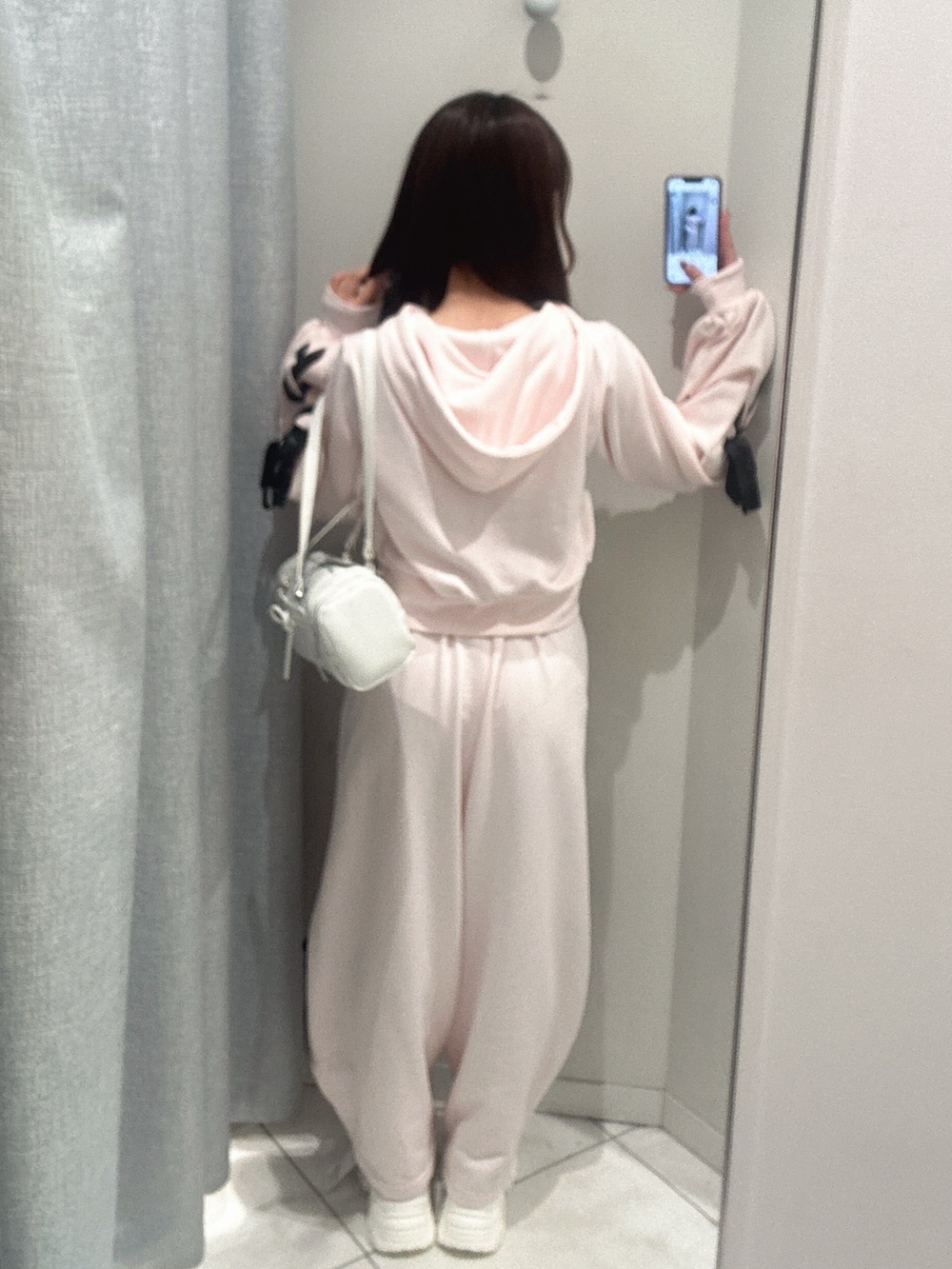 ホワイト系のスニーカー、ピンク系のスウェットパンツ、ピンク系のパーカーを着用したレディースの冬コーディネートの4枚目の写真