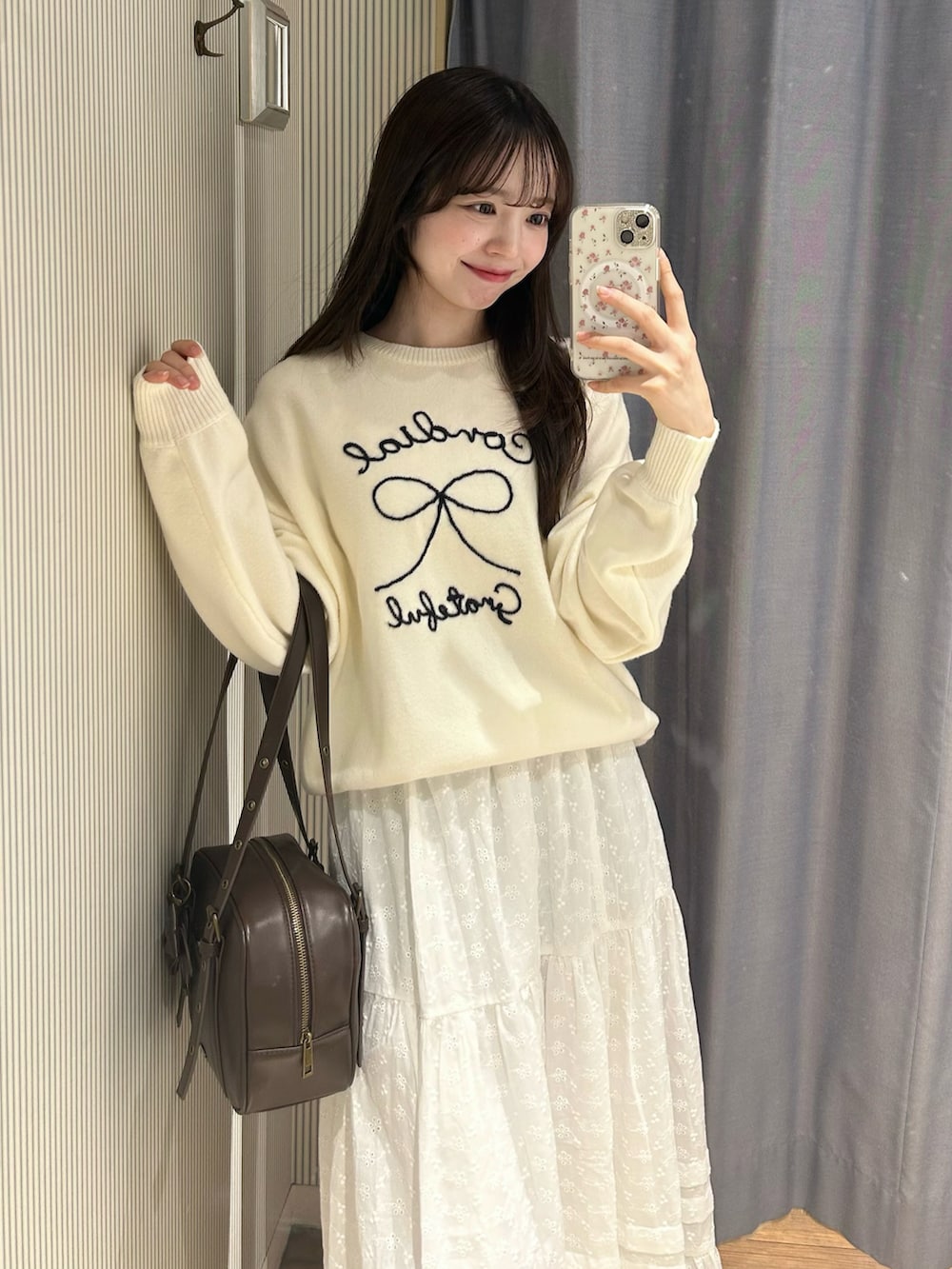 ピンク系のニット/セーター、ホワイト系のスカート、ホワイト系のショルダーバッグを着用したレディースの冬コーディネートの3枚目の写真