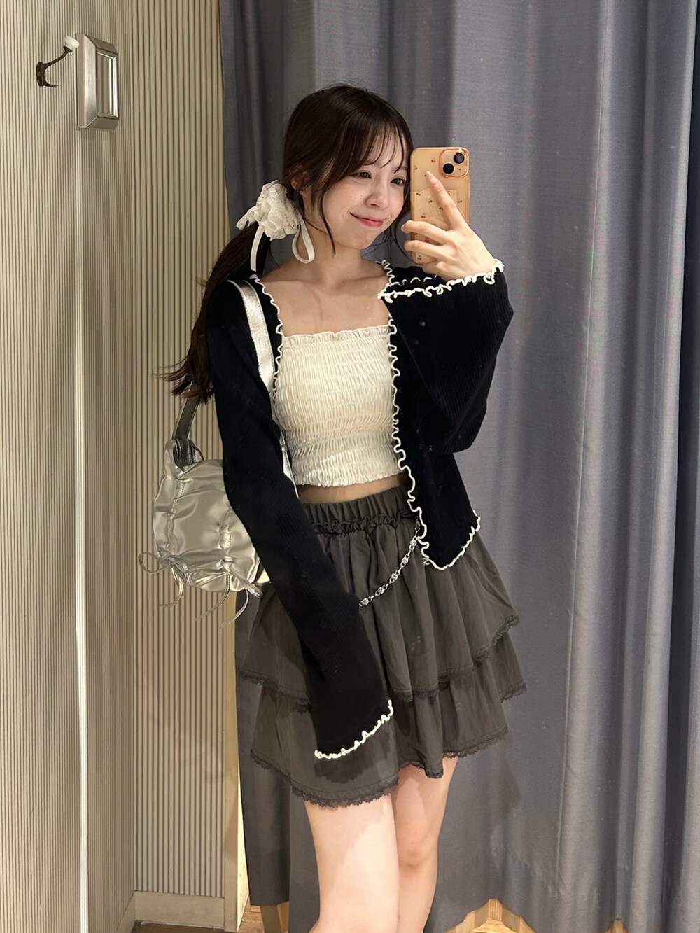 グレー系のスカート、ホワイト系のキャミソール、ブラック系のカーディガン/ボレロを着用したレディースの秋コーディネートの2枚目の写真