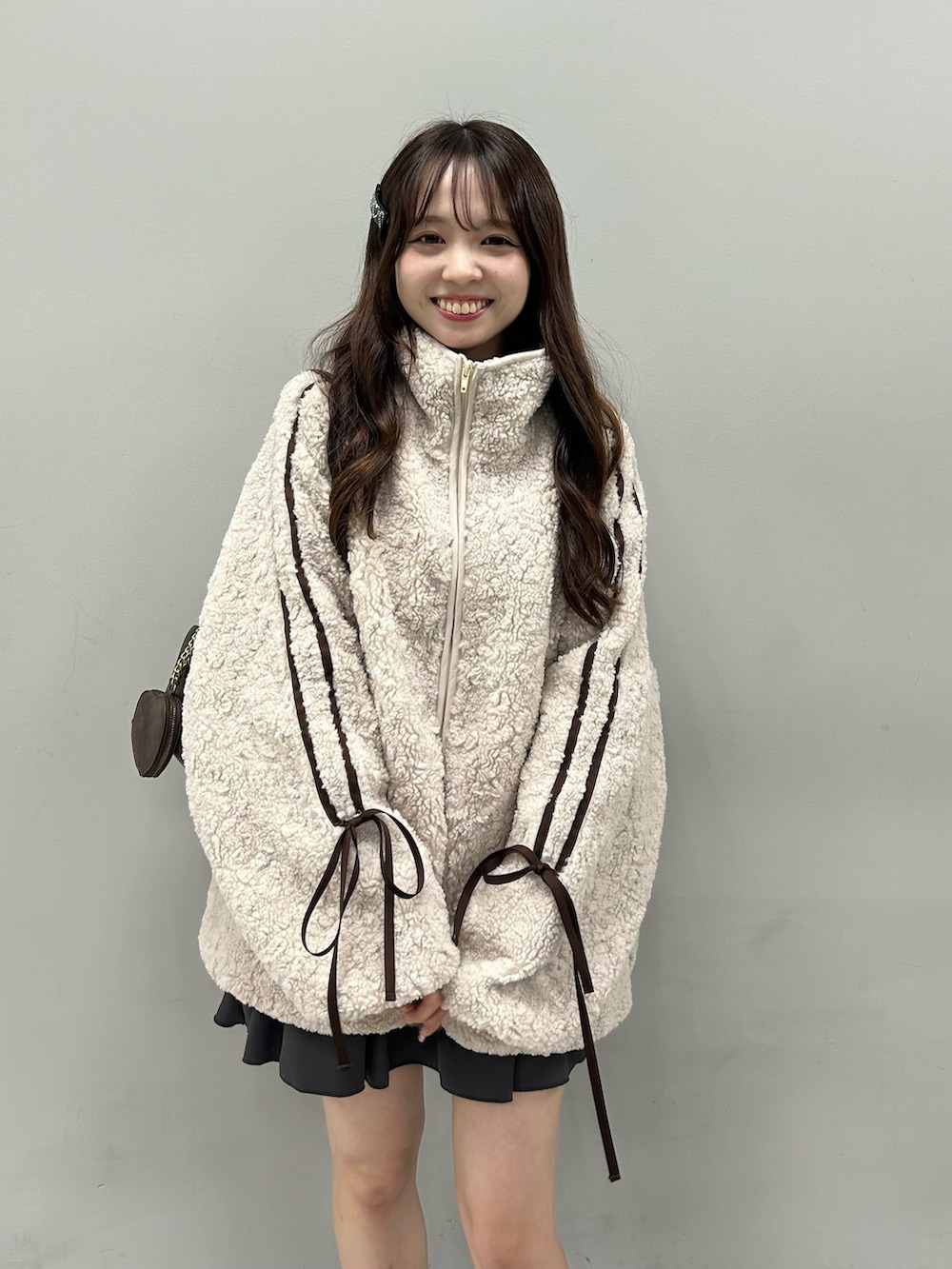 ベージュ系のブルゾン、ブラック系のショルダーバッグ、グレー系のスカートを着用したレディースの冬コーディネートの3枚目の写真