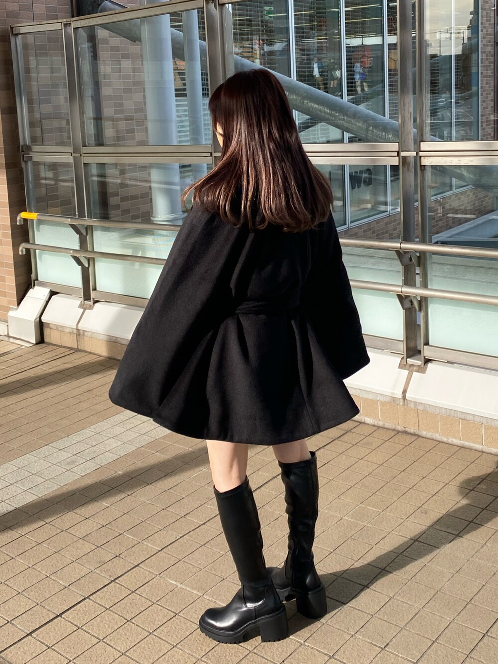 ブラック系のブーツ、ブラック系のポンチョ、ピンク系のニット/セーターを着用したレディースの冬コーディネートの3枚目の写真