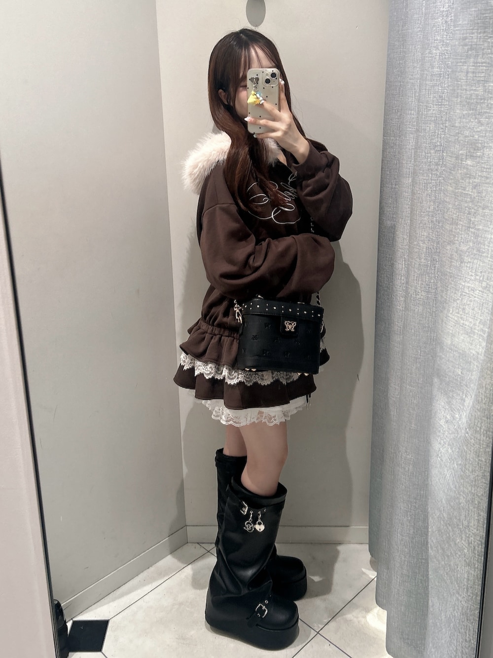 ブラック系のブーツ、ブラウン系のパーカー、ブラック系のショルダーバッグを着用したレディースの秋コーディネートの8枚目の写真