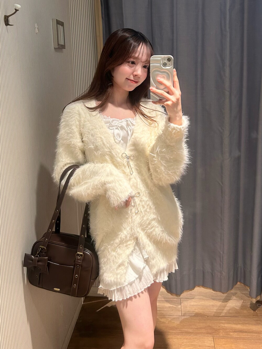 ブラウン系のショルダーバッグ、ホワイト系のカーディガン/ボレロ、ホワイト系のワンピースを着用したレディースの冬コーディネートの2枚目の写真