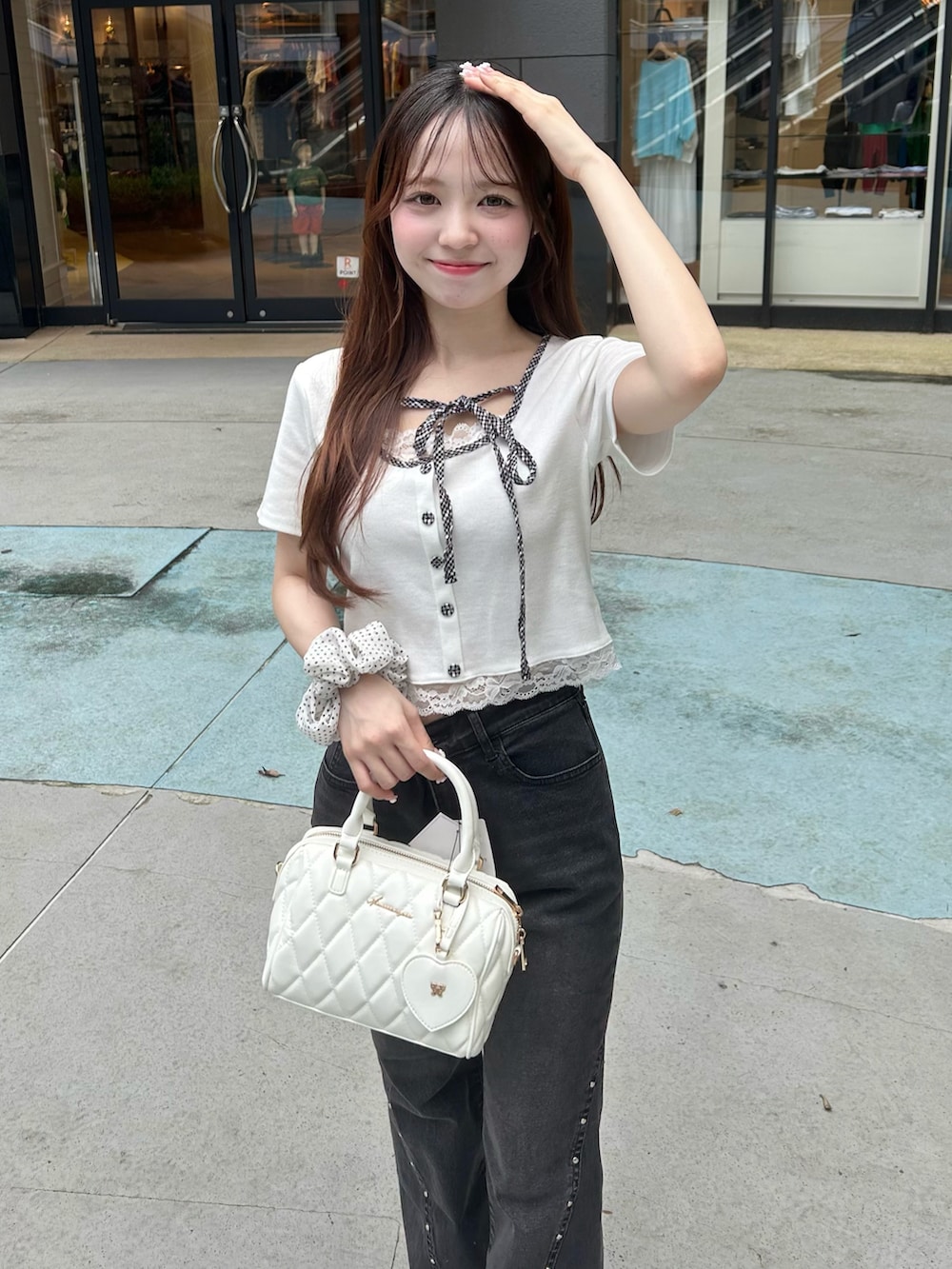 ブラック系のデニムパンツ、ホワイト系のボストンバッグ、ホワイト系のスニーカーを着用したレディースの夏コーディネートの4枚目の写真