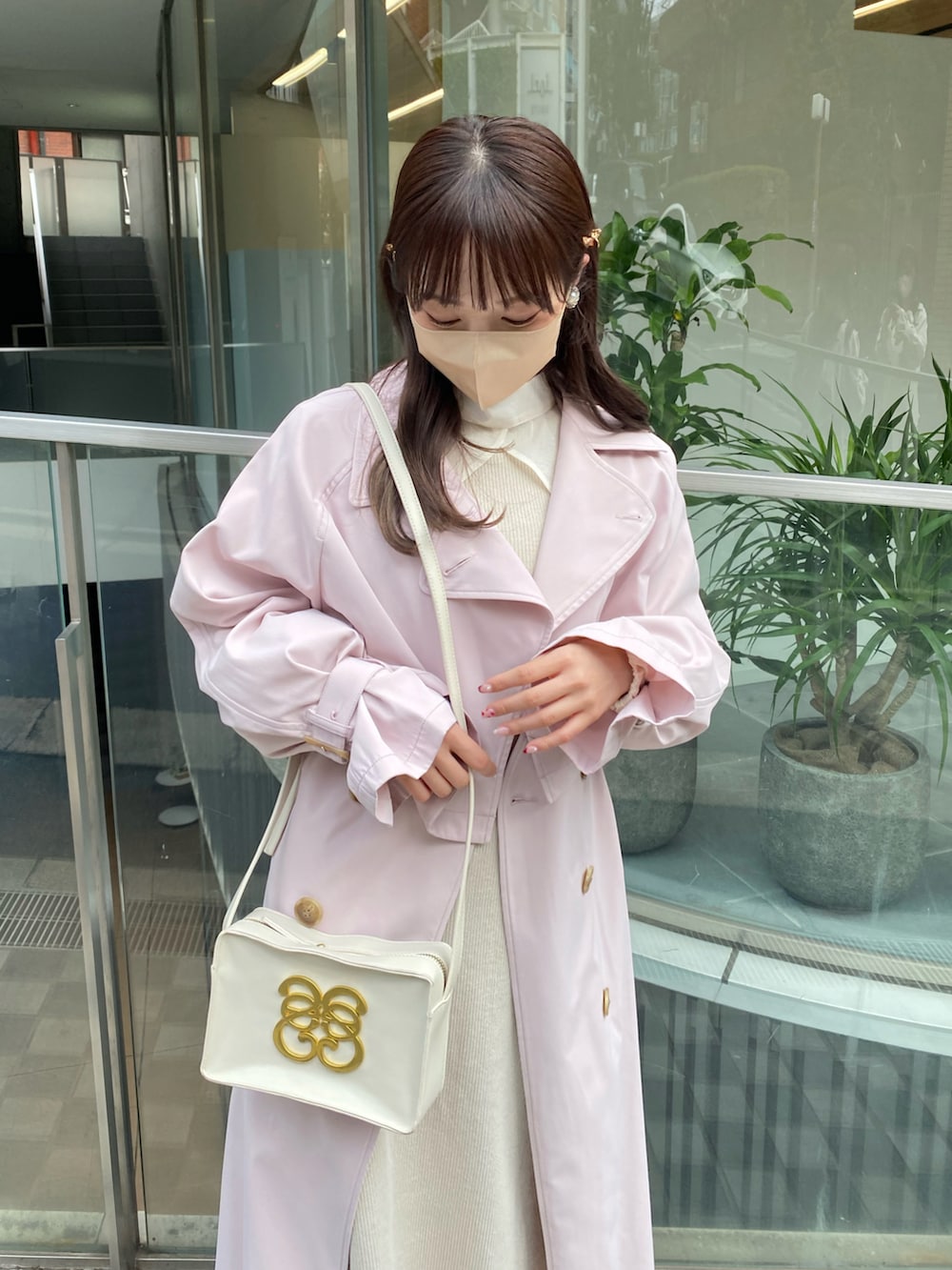 ピンク系のトレンチコート、ホワイト系のワンピース、ホワイト系のショルダーバッグを着用したレディースの春コーディネートの4枚目の写真