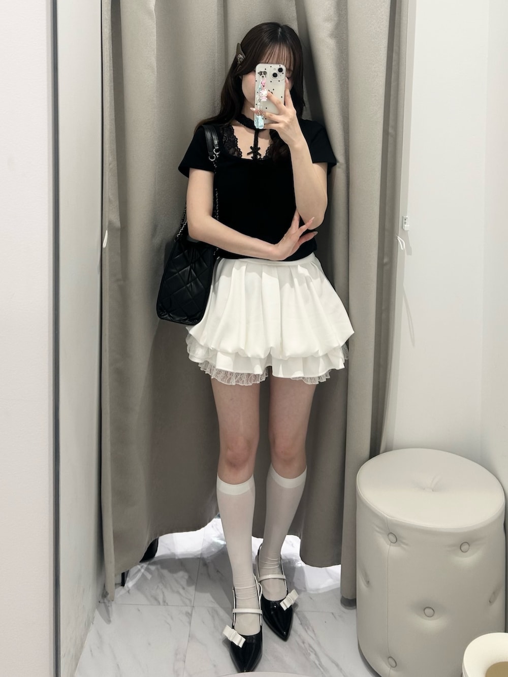 ブラック系のトートバッグ、ホワイト系のスカート、ブラック系のTシャツ/カットソーを着用したレディースの春コーディネートの5枚目の写真