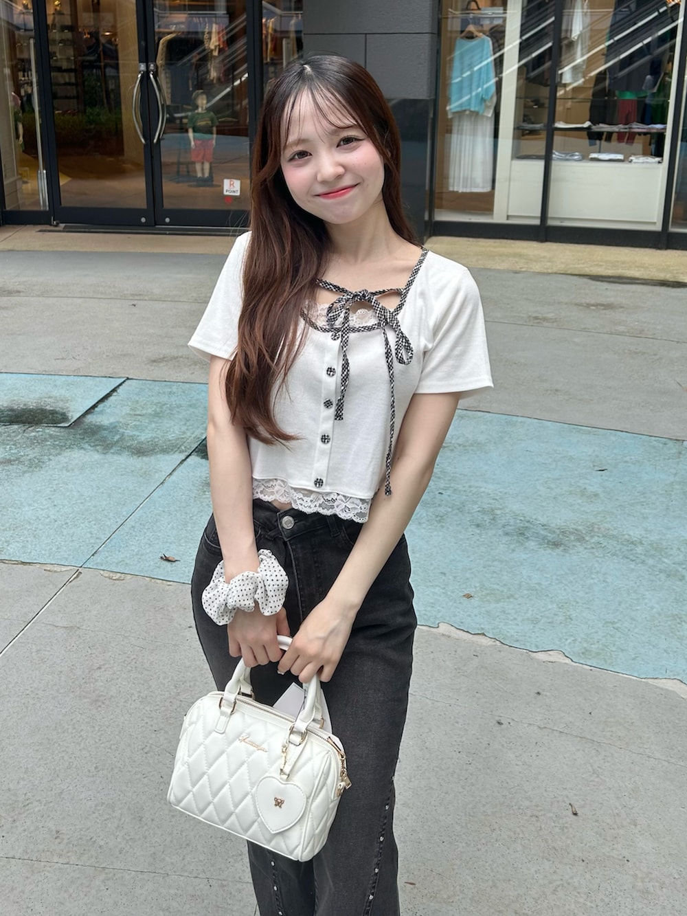 ブラック系のデニムパンツ、ホワイト系のボストンバッグ、ホワイト系のスニーカーを着用したレディースの夏コーディネートの5枚目の写真