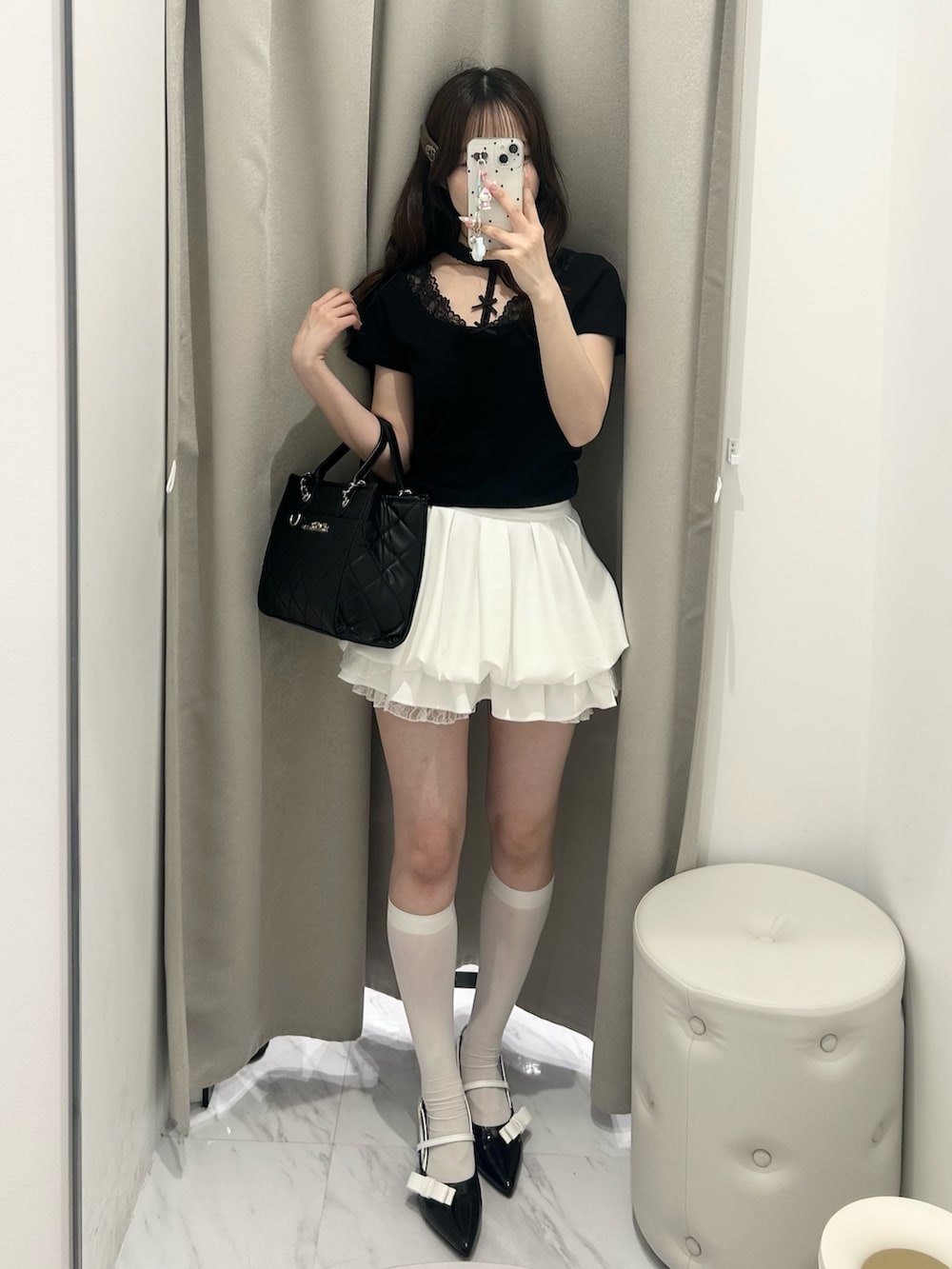 ブラック系のトートバッグ、ホワイト系のスカート、ブラック系のTシャツ/カットソーを着用したレディースの春コーディネートの4枚目の写真