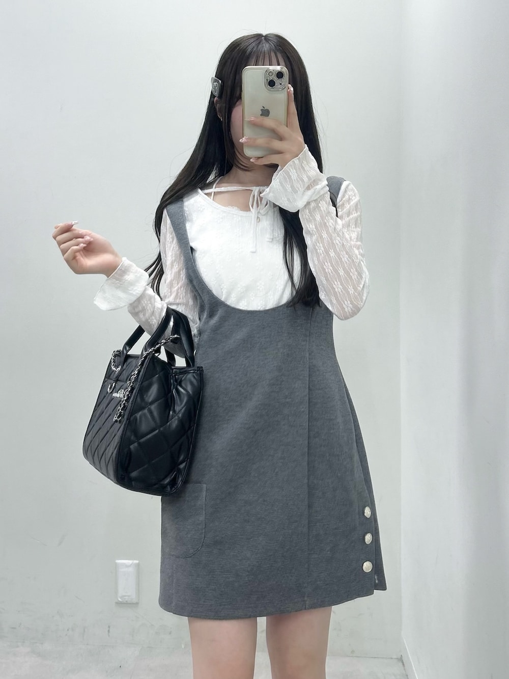 ホワイト系のTシャツ/カットソー、グレー系のジャンパースカート、ブラック系のトートバッグを着用したレディースの冬コーディネートの2枚目の写真