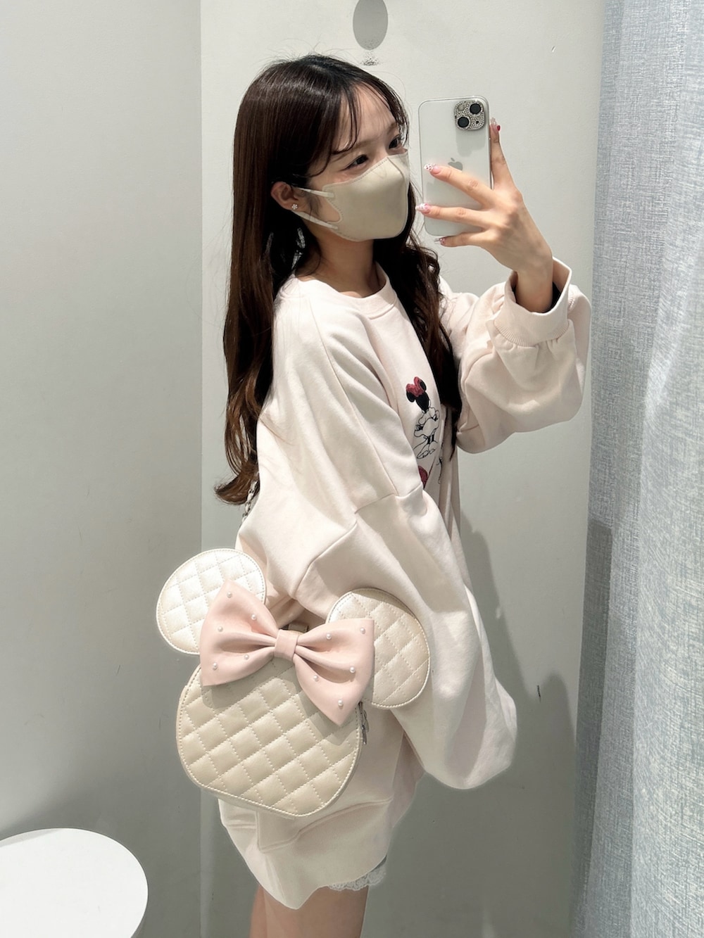 ピンク系のスウェット、ピンク系のショルダーバッグを着用したレディースの冬コーディネートの2枚目の写真