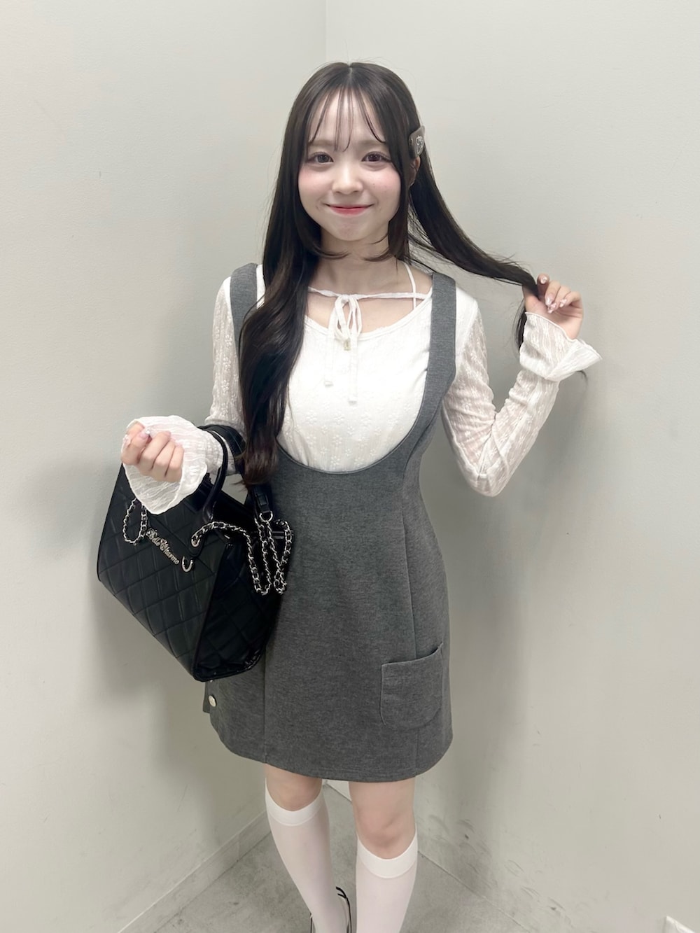 ホワイト系のTシャツ/カットソー、グレー系のジャンパースカート、ブラック系のトートバッグを着用したレディースの冬コーディネートの6枚目の写真