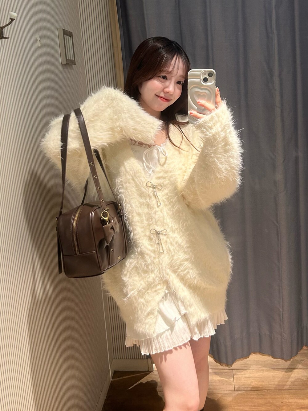 ブラウン系のショルダーバッグ、ホワイト系のワンピース、ホワイト系のカーディガン/ボレロを着用したレディースの冬コーディネートの2枚目の写真