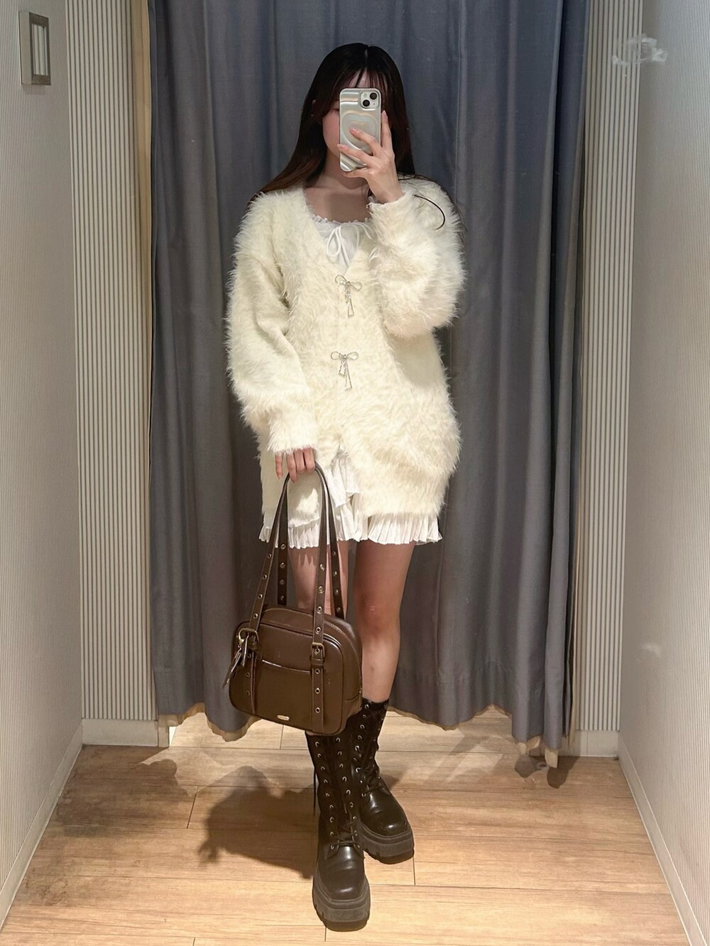 ブラウン系のショルダーバッグ、ホワイト系のカーディガン/ボレロ、ホワイト系のワンピースを着用したレディースの冬コーディネートの4枚目の写真