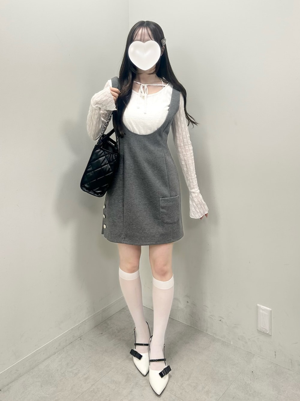 ホワイト系のTシャツ/カットソー、グレー系のジャンパースカート、ブラック系のトートバッグを着用したレディースの冬コーディネートの3枚目の写真