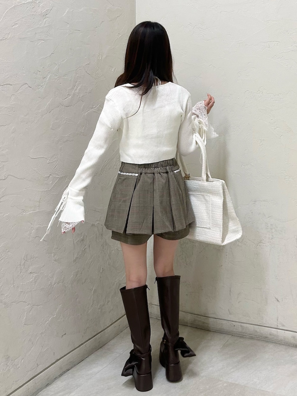 ブラウン系のその他パンツ、ホワイト系のカーディガン/ボレロ、ブラック系のブーツを着用したレディースの秋コーディネートの5枚目の写真