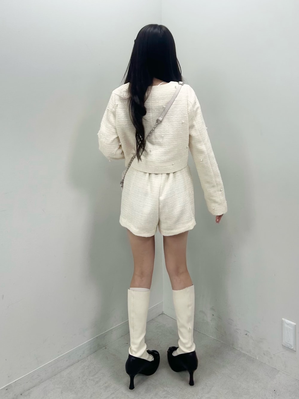 ホワイト系のノーカラージャケット、ホワイト系のブーツ、ホワイト系のショルダーバッグを着用したレディースの春コーディネートの4枚目の写真