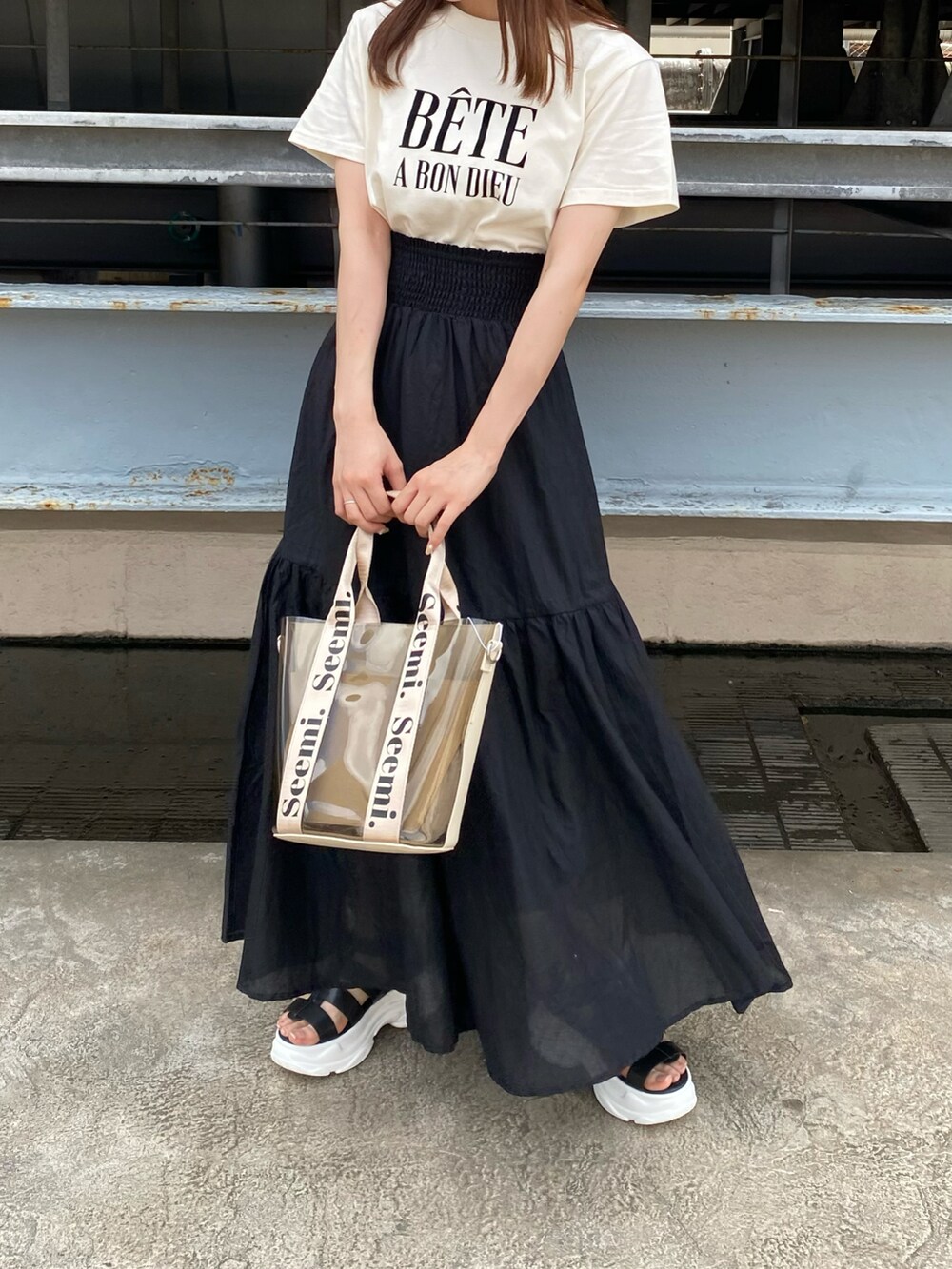 ブラック系のサンダル、ホワイト系のTシャツ/カットソー、ブラック系のスカートを着用したレディースの夏コーディネートの2枚目の写真