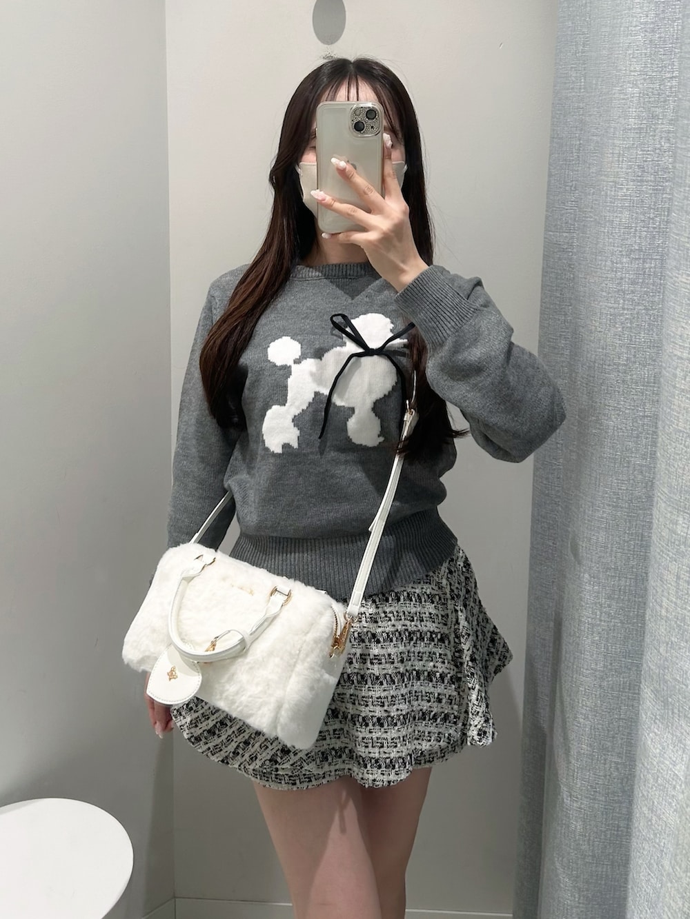 グレー系のニット/セーター、ブラック系のスカート、ホワイト系のショルダーバッグを着用したレディースの秋コーディネートの4枚目の写真