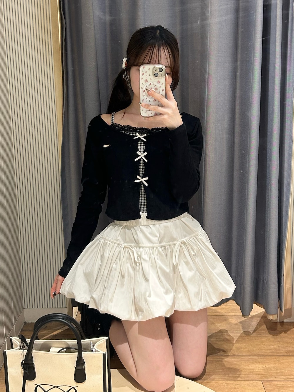 ホワイト系のトートバッグ、ブラック系のTシャツ/カットソー、ホワイト系のスカートを着用したレディースの春コーディネートの2枚目の写真