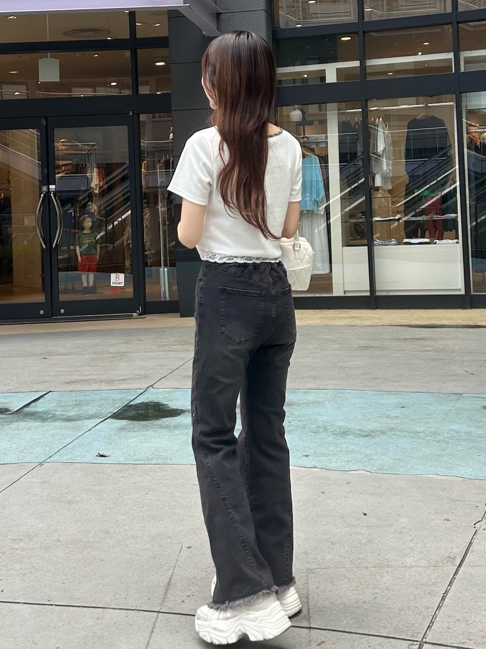 ブラック系のデニムパンツ、ホワイト系のボストンバッグ、ホワイト系のスニーカーを着用したレディースの夏コーディネートの3枚目の写真