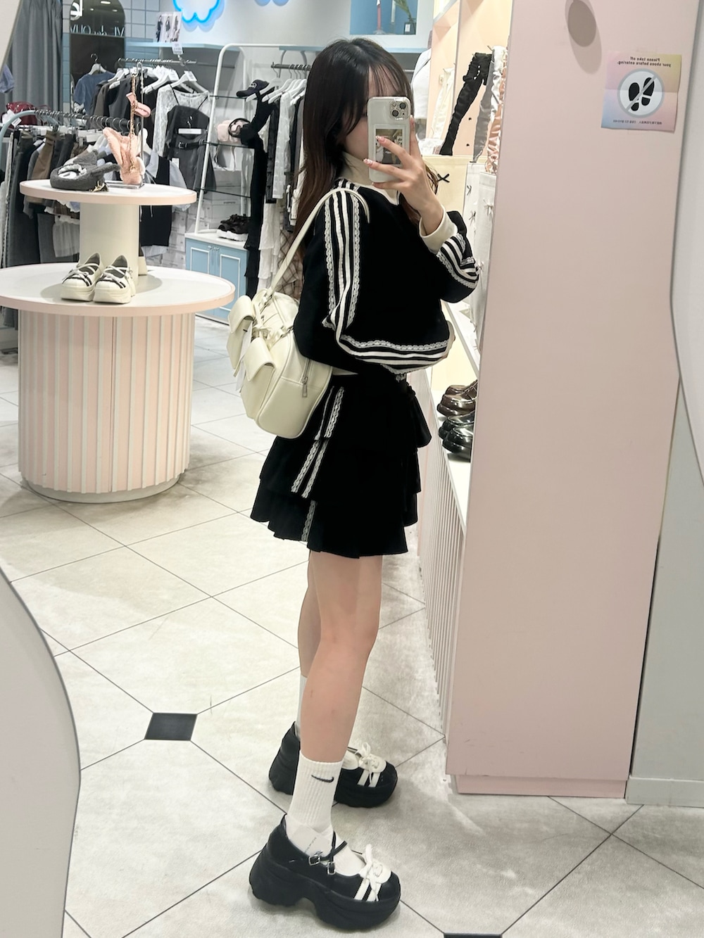 ブラック系のジャージ、ブラック系のスカート、ホワイト系のバッグを着用したレディースの夏コーディネートの4枚目の写真