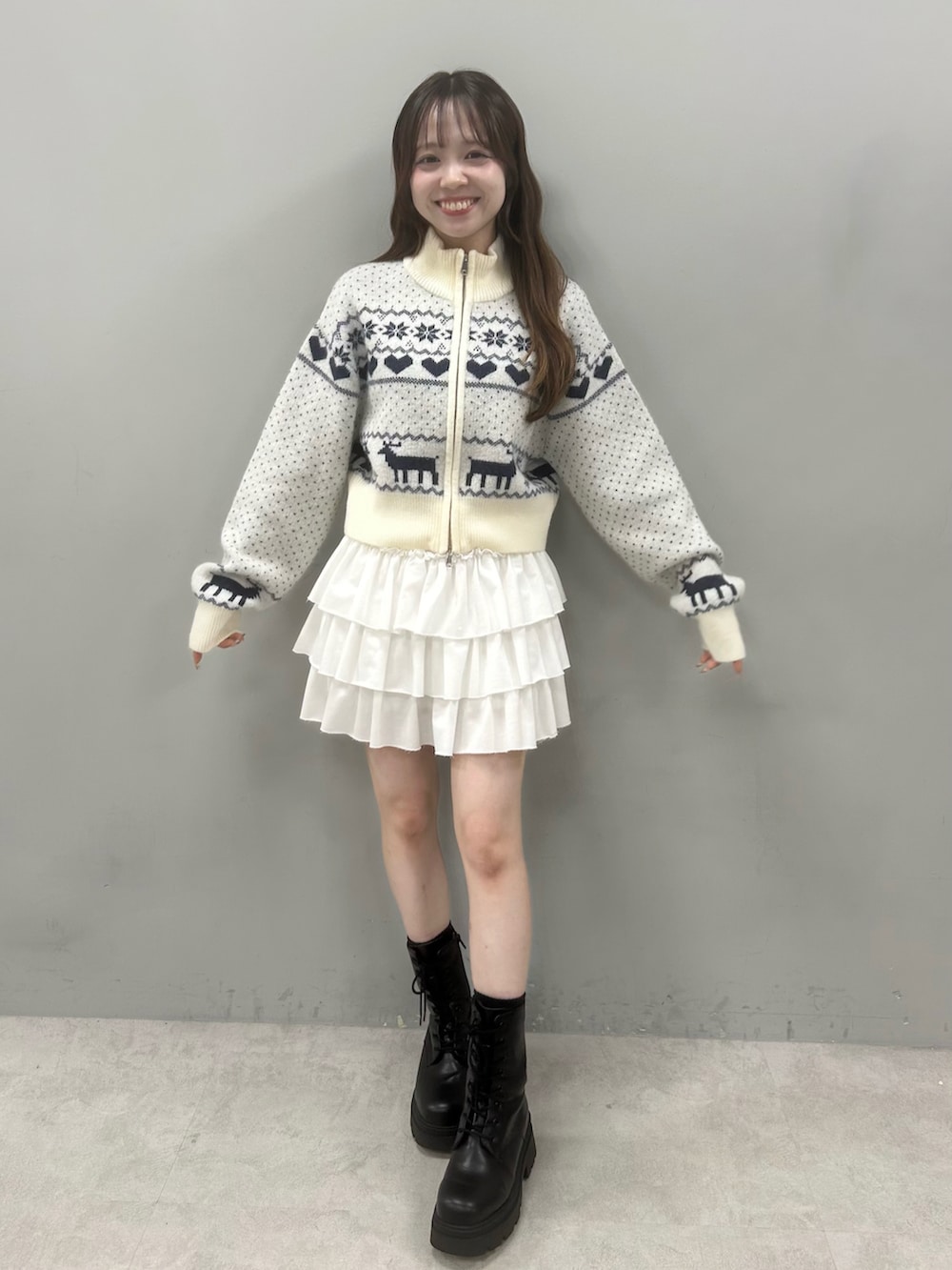 ホワイト系のニット/セーター、ホワイト系のスカート、ブラック系のブーツを着用したレディースの秋コーディネートの2枚目の写真