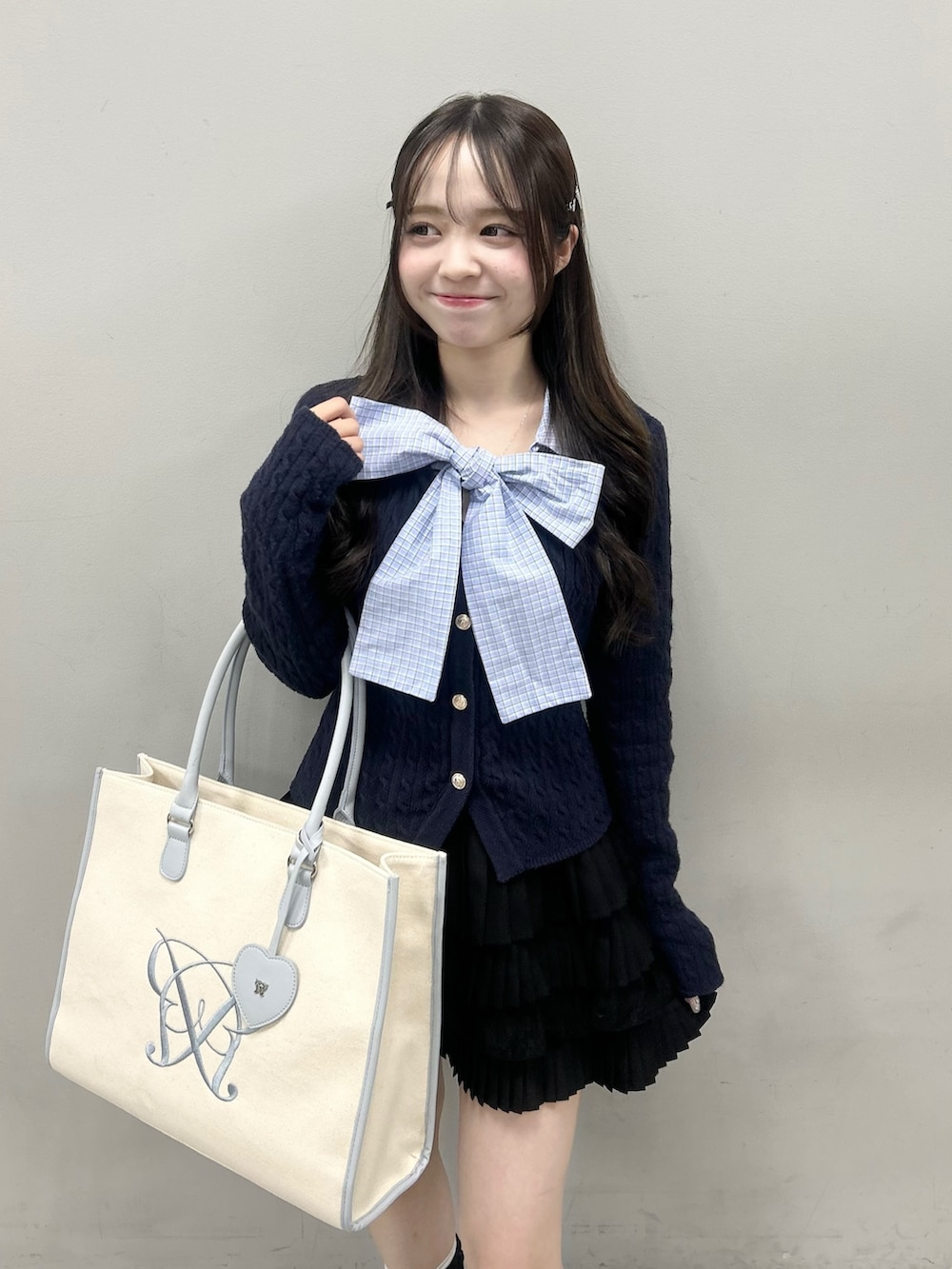 ブルー系のニット/セーター、ブラック系のスカート、ブルー系のトートバッグを着用したレディースの冬コーディネートの3枚目の写真
