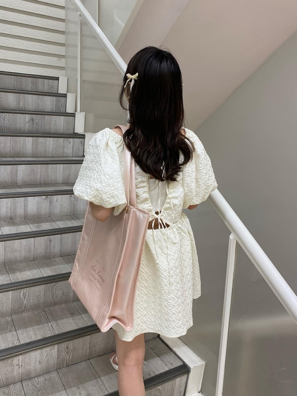 ピンク系のトートバッグ、ホワイト系のチュニックを着用したレディースの夏コーディネートの4枚目の写真