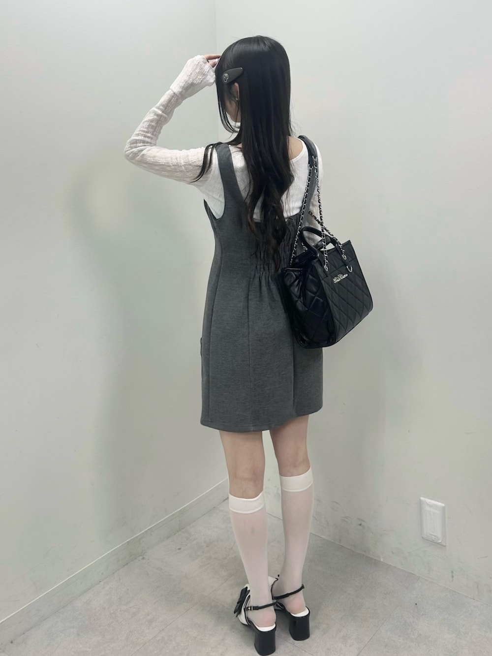 ホワイト系のTシャツ/カットソー、グレー系のジャンパースカート、ブラック系のトートバッグを着用したレディースの冬コーディネートの5枚目の写真