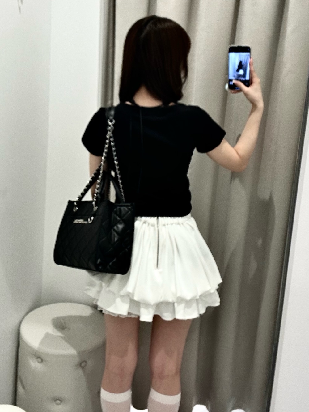 ブラック系のトートバッグ、ホワイト系のスカート、ブラック系のTシャツ/カットソーを着用したレディースの春コーディネートの7枚目の写真