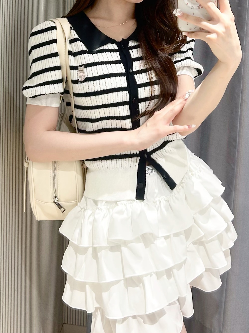 その他のポロシャツ、ホワイト系のスカート、ホワイト系のショルダーバッグを着用したレディースの夏コーディネートの3枚目の写真