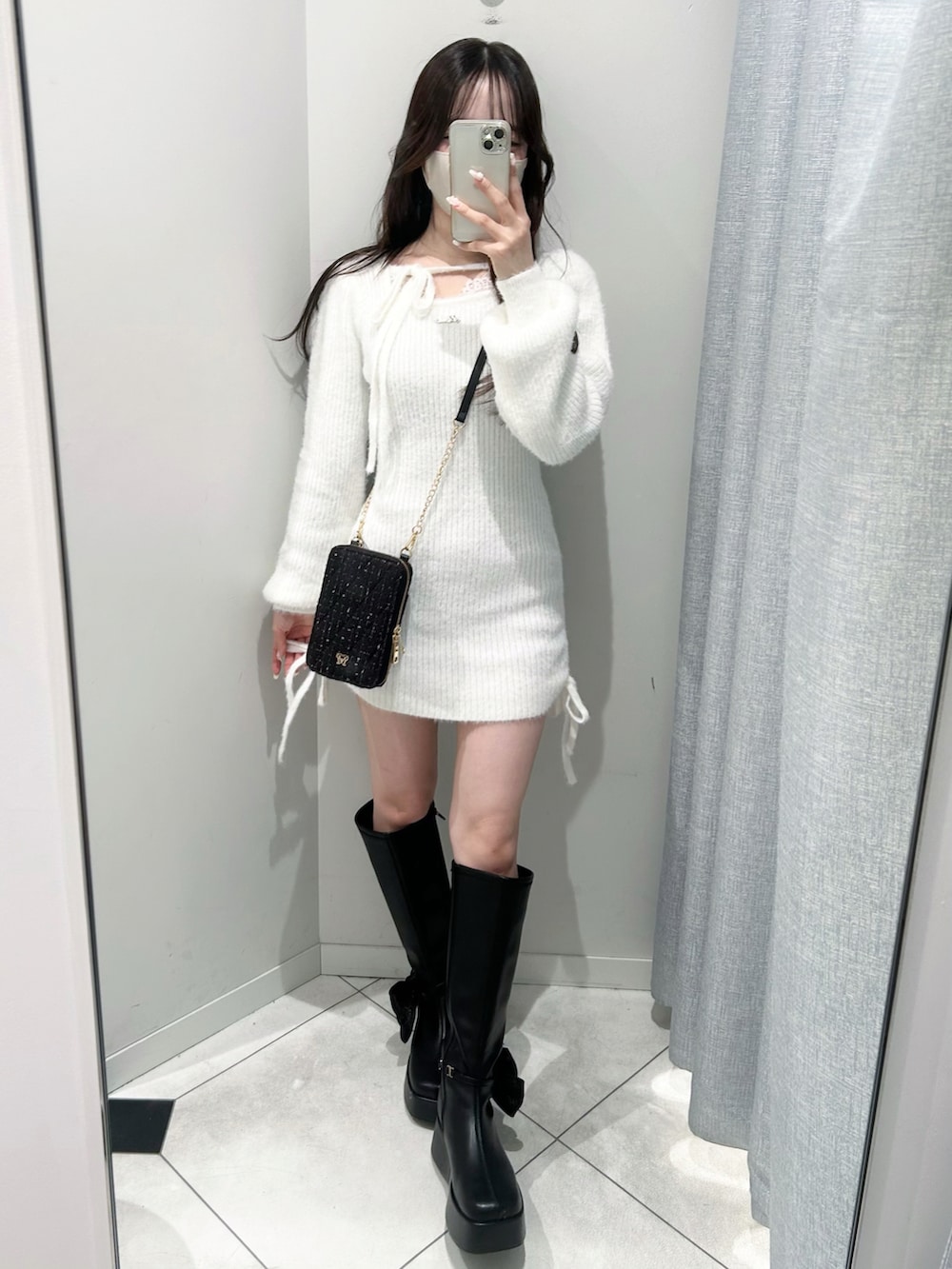ブラック系のショルダーバッグ、ブラック系のブーツ、ホワイト系のワンピースを着用したレディースの秋コーディネートの3枚目の写真