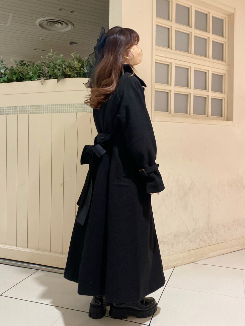 ブラック系のステンカラーコート、ブラック系のローファー、ブラック系のワンピースを着用したレディースの秋コーディネートの3枚目の写真