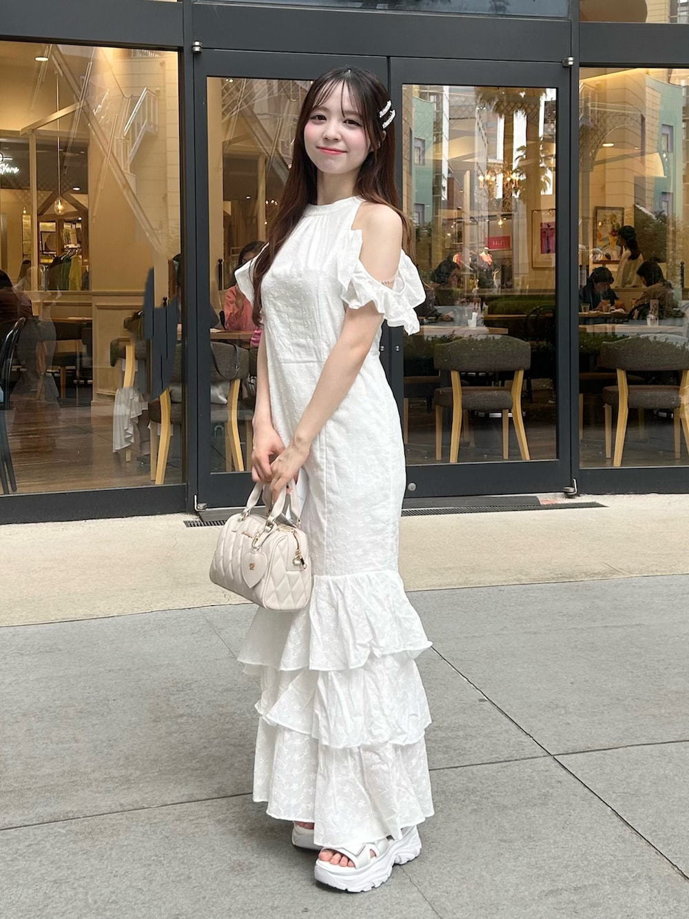 ホワイト系のワンピース、ベージュ系のボストンバッグ、ホワイト系のサンダルを着用したレディースの夏コーディネートの2枚目の写真