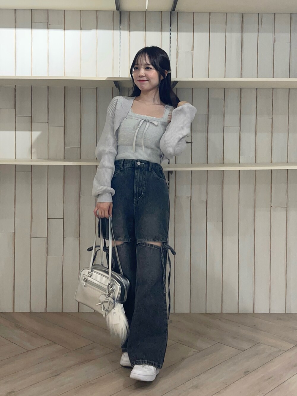 ブルー系のアンサンブル、ブラック系のデニムパンツ、シルバー系のショルダーバッグを着用したレディースの秋コーディネートの3枚目の写真