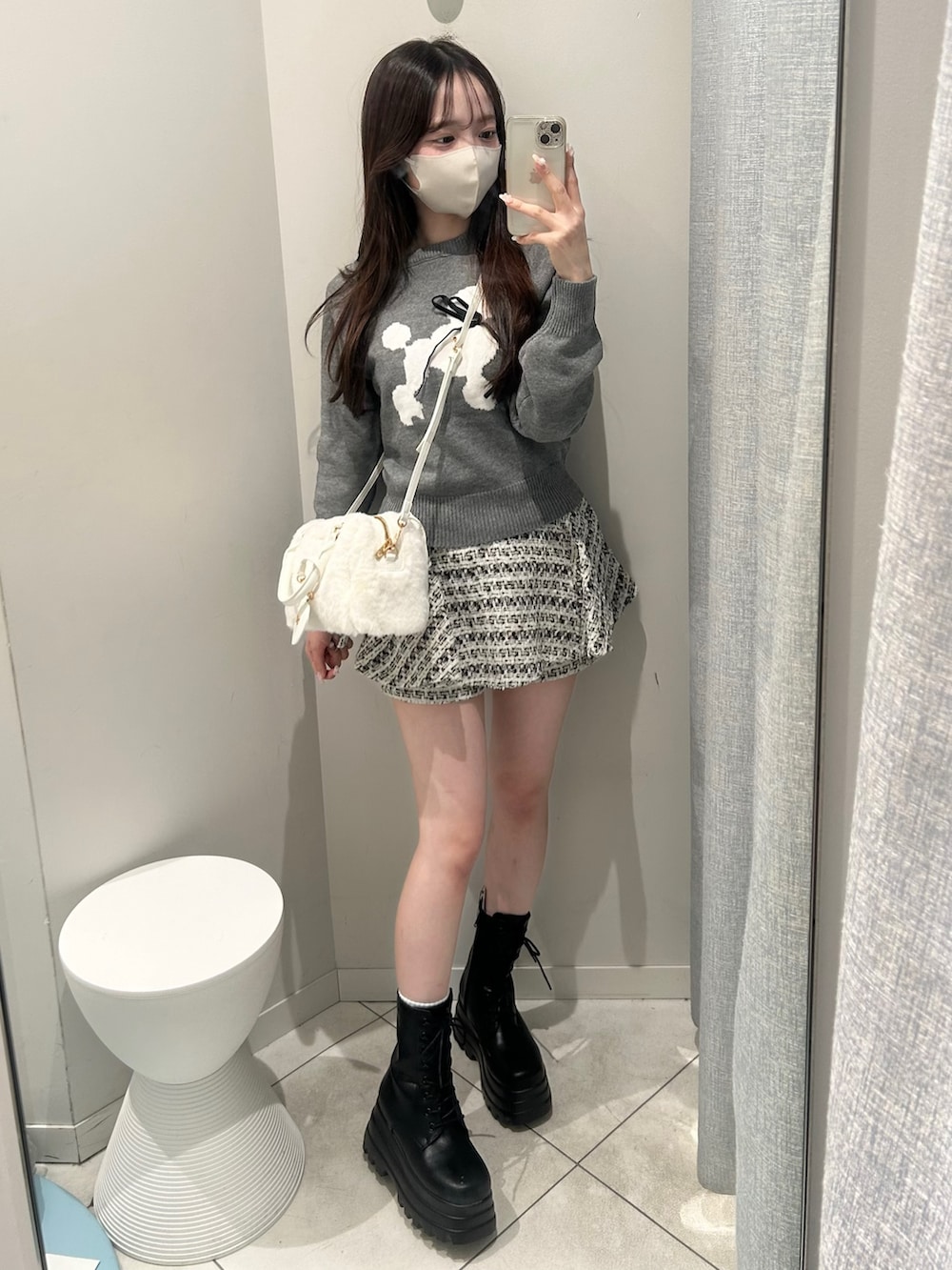 グレー系のニット/セーター、ブラック系のスカート、ホワイト系のショルダーバッグを着用したレディースの秋コーディネートの2枚目の写真