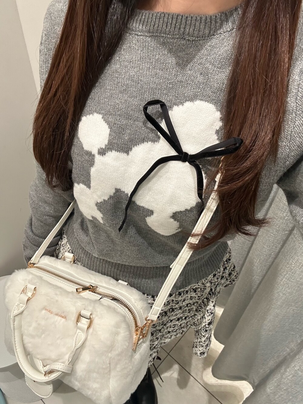 グレー系のニット/セーター、ブラック系のスカート、ホワイト系のショルダーバッグを着用したレディースの秋コーディネートの6枚目の写真