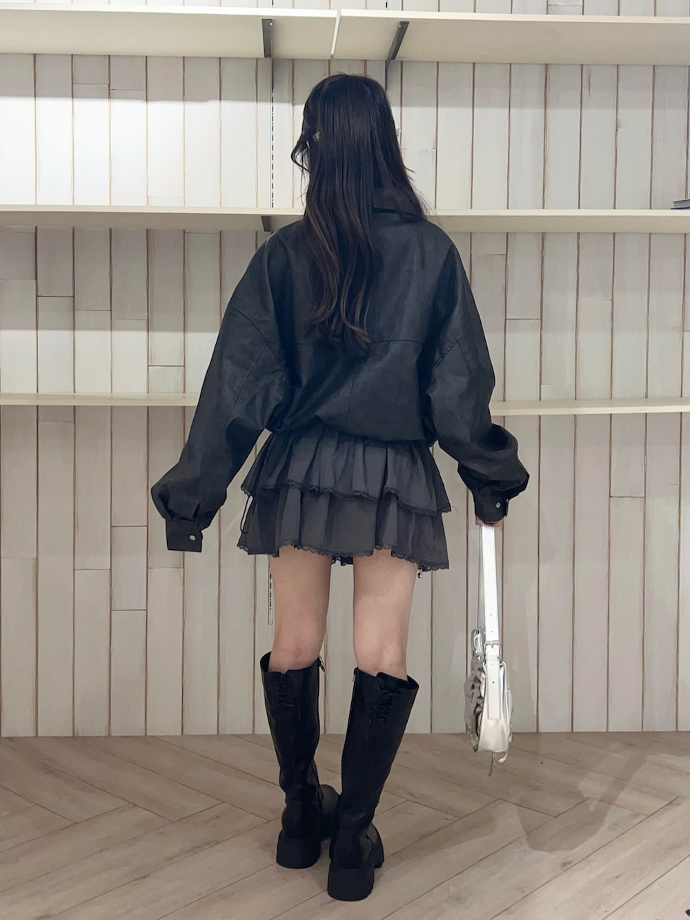 ブラック系のブルゾン、グレー系のスカート、ブラック系のブーツを着用したレディースの秋コーディネートの5枚目の写真