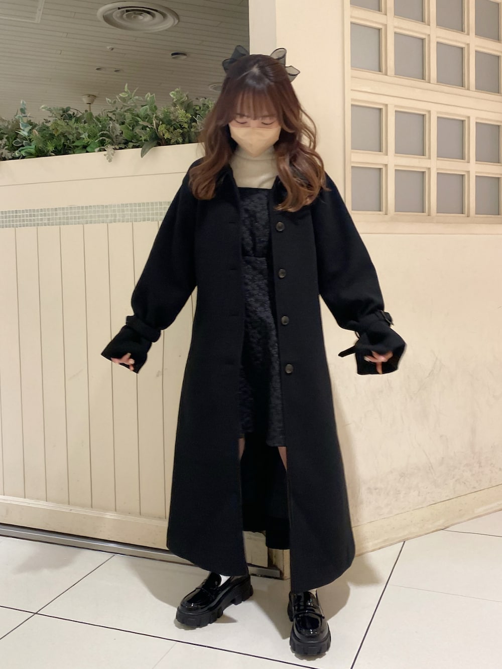 ブラック系のステンカラーコート、ブラック系のローファー、ブラック系のワンピースを着用したレディースの秋コーディネートの2枚目の写真