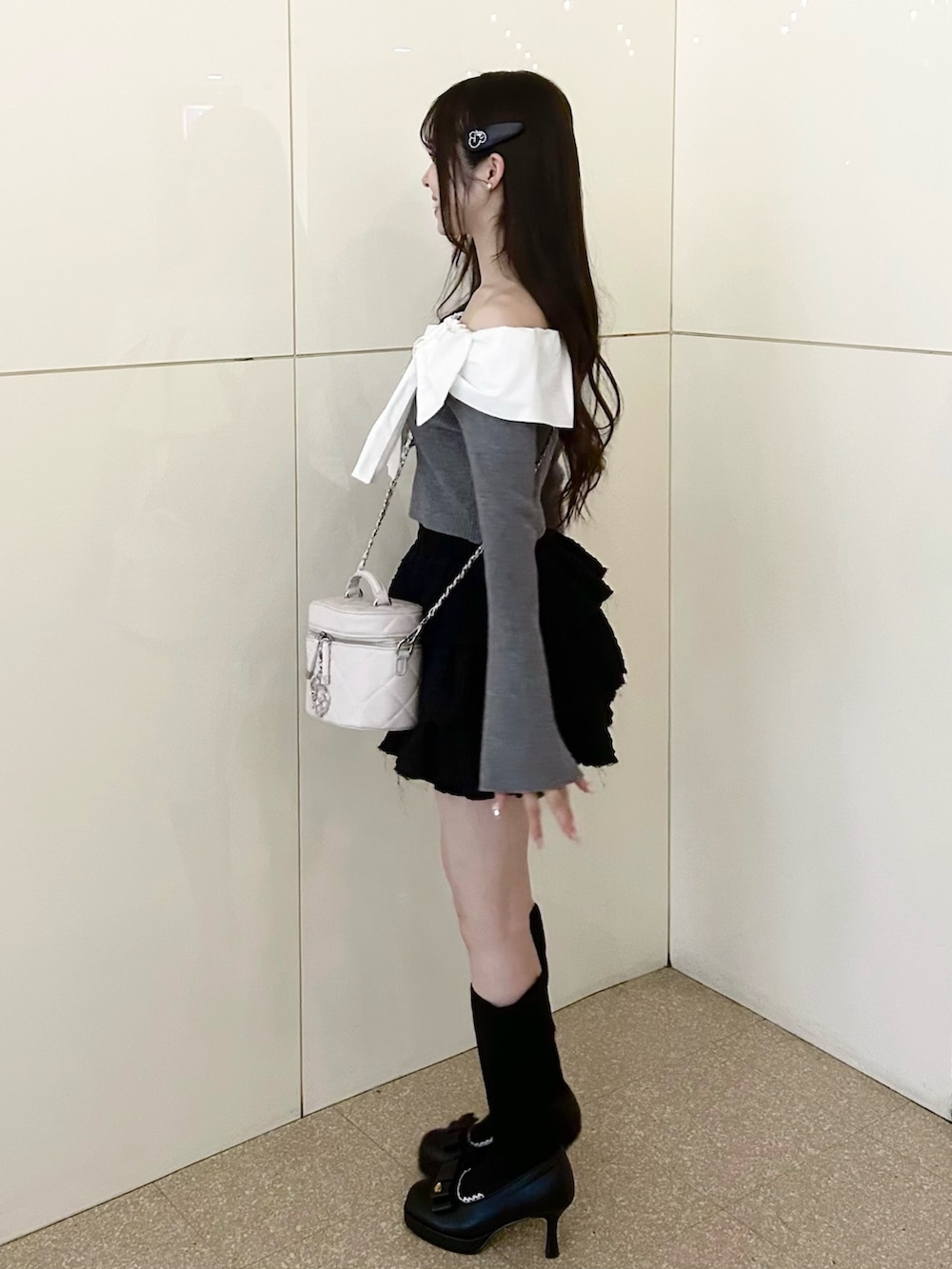 グレー系のニット/セーター、ホワイト系のショルダーバッグ、ブラック系のスカートを着用したレディースの冬コーディネートの2枚目の写真