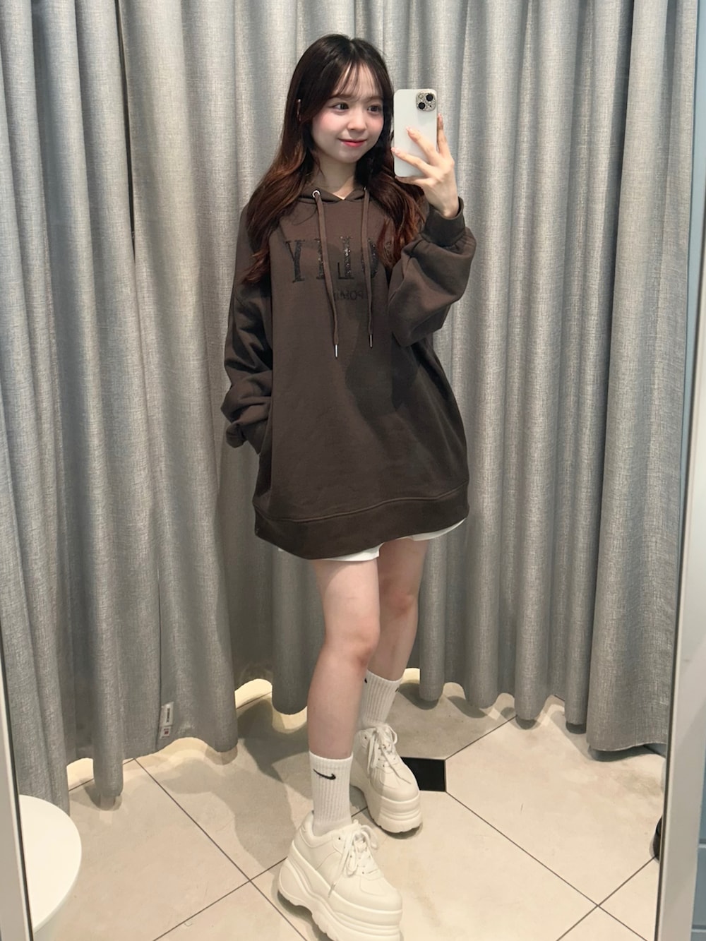 ブラック系のパーカー、ホワイト系のスカートを着用したレディースの秋コーディネートの2枚目の写真