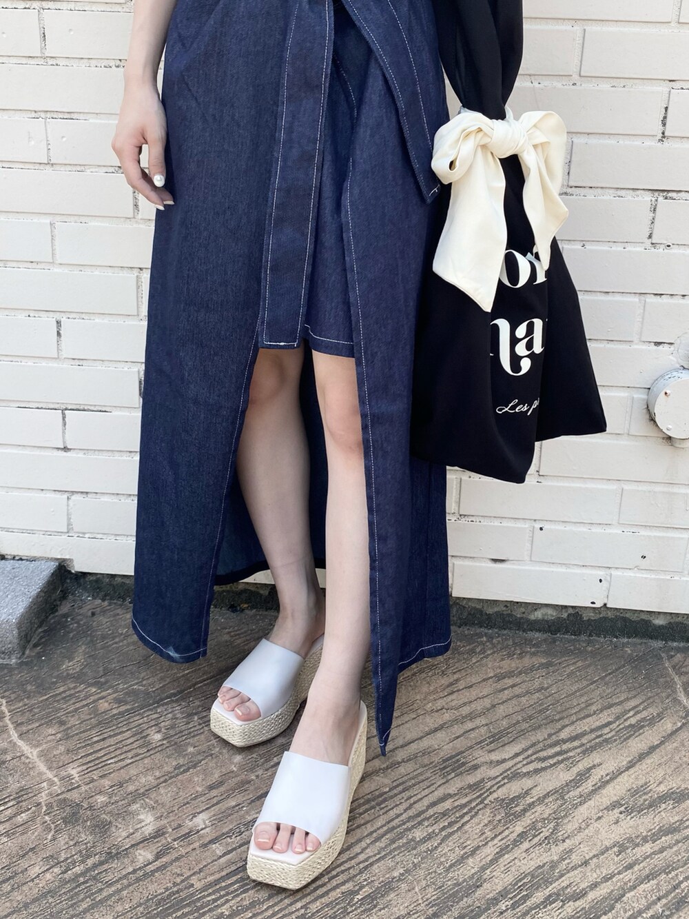 ホワイト系のサンダル、ブルー系のジャンパースカート、ブラック系のトートバッグを着用したレディースの春コーディネートの3枚目の写真