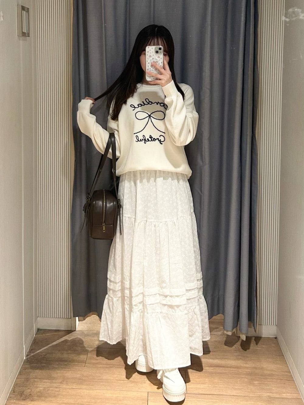 ピンク系のニット/セーター、ホワイト系のスカート、ホワイト系のショルダーバッグを着用したレディースの冬コーディネートの2枚目の写真